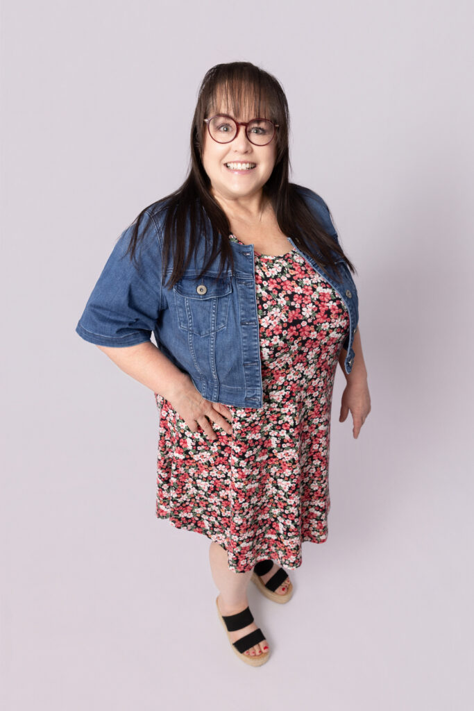 Smiling woman in floral dress and jacket.