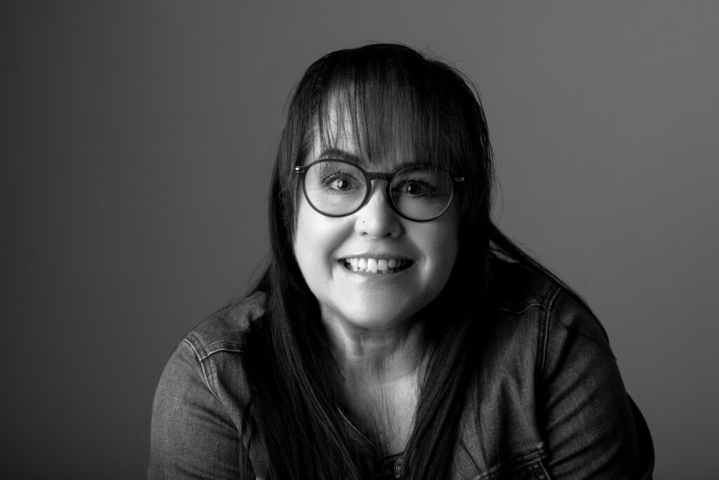 Smiling woman in glasses, black and white.