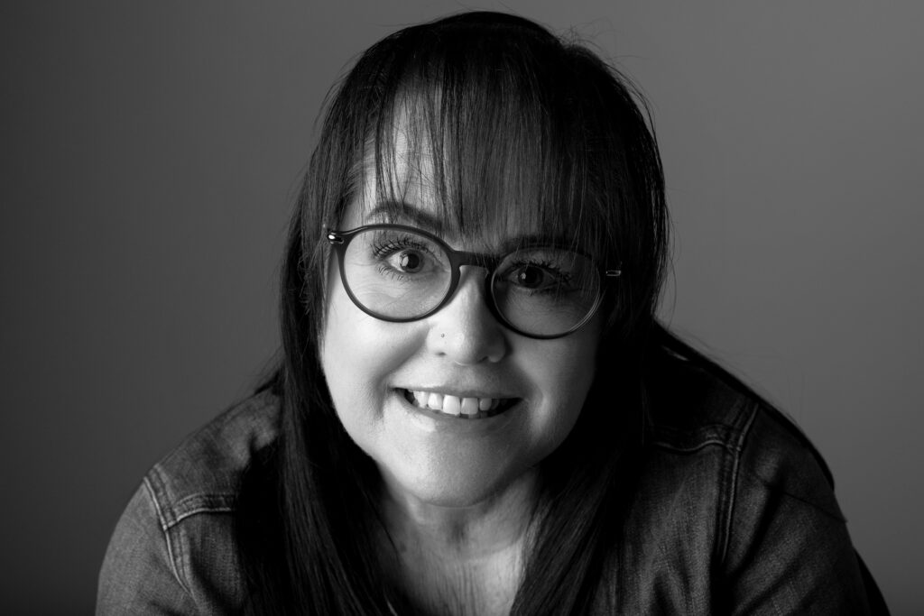 Smiling woman with glasses, black and white.