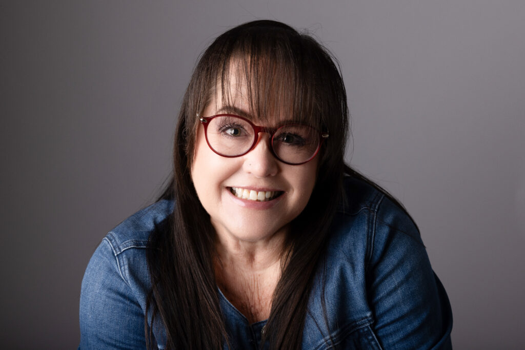 Smiling woman with glasses and long hair.