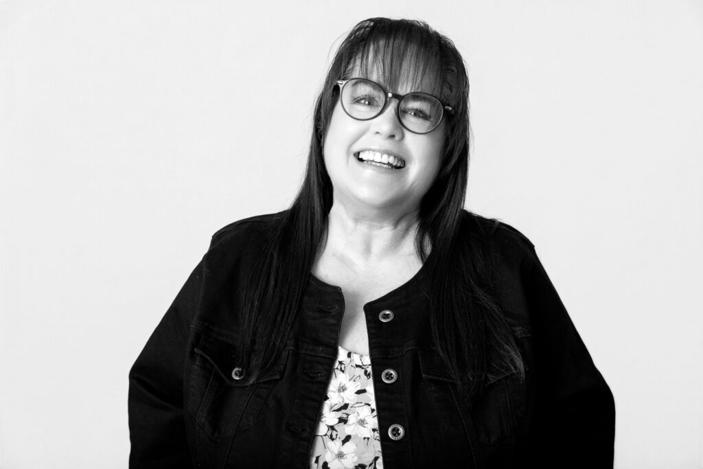 Smiling woman in glasses, black and white.