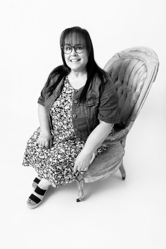 Woman seated on vintage chair, smiling.