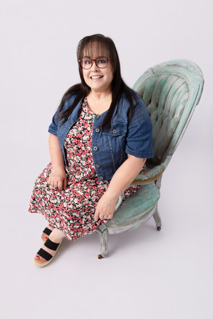 Smiling woman seated on vintage chair.